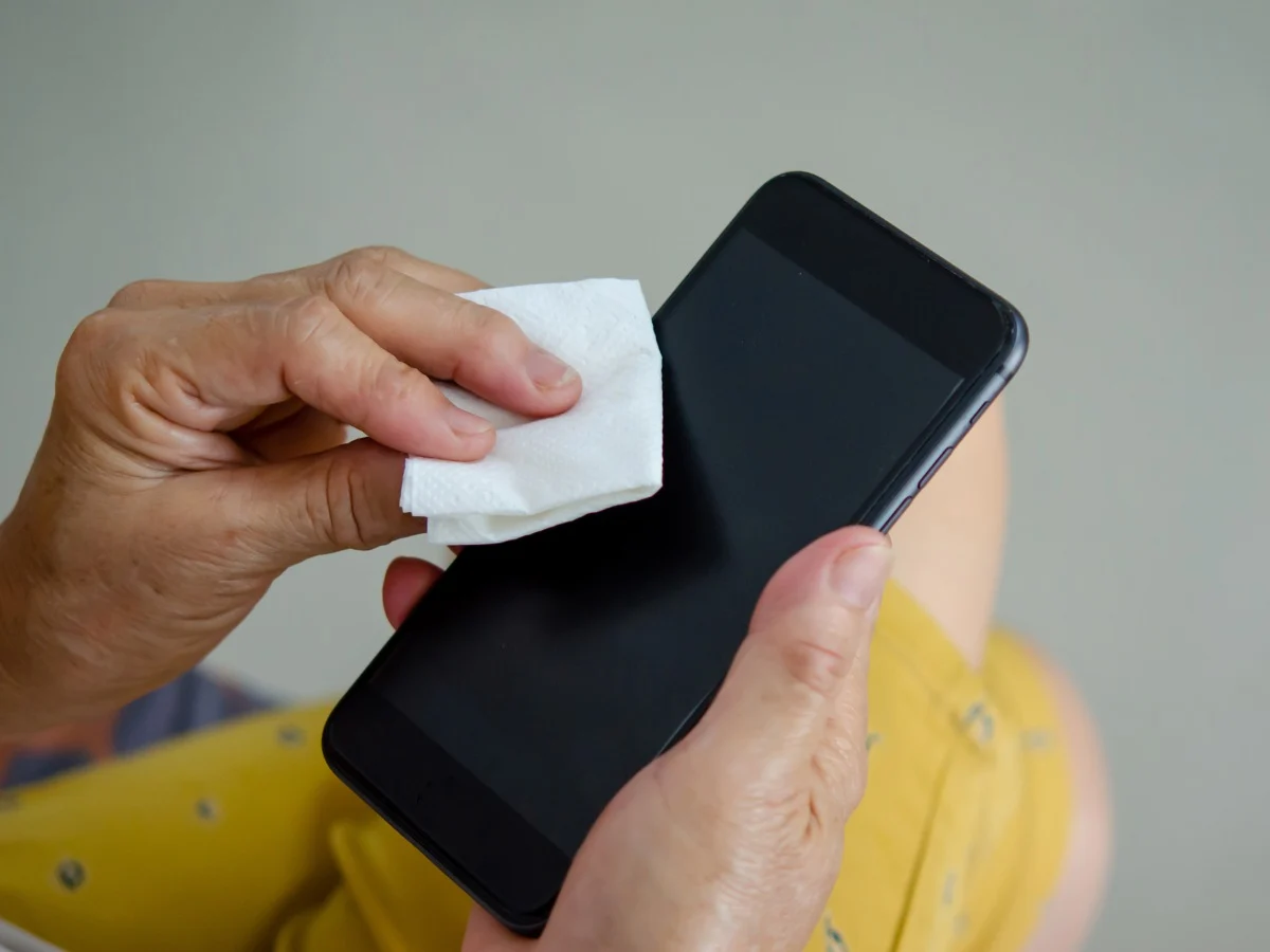 Persona limpiando la pantalla de un teléfono móvil con un paño de microfibra