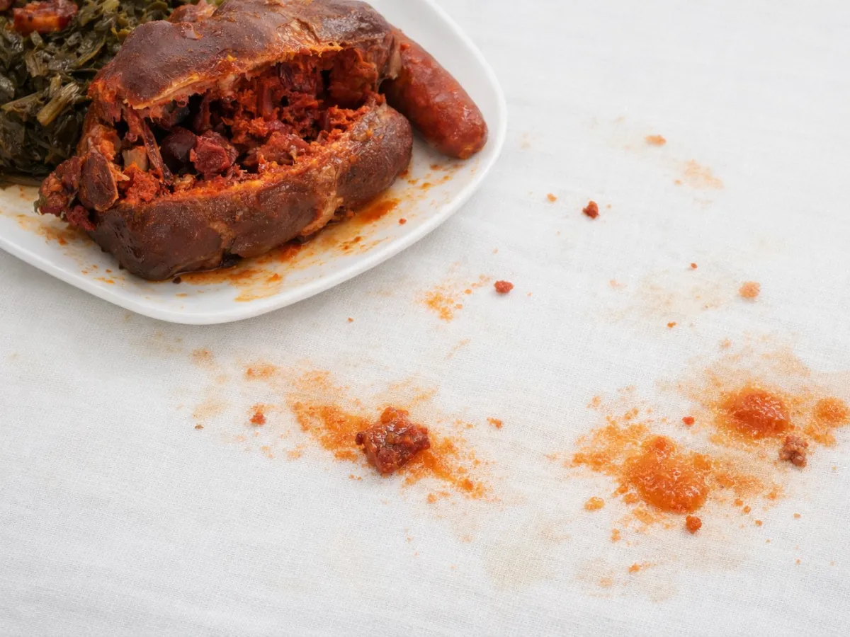 Close up of white tablecloth with red paprika stain and botillo grease