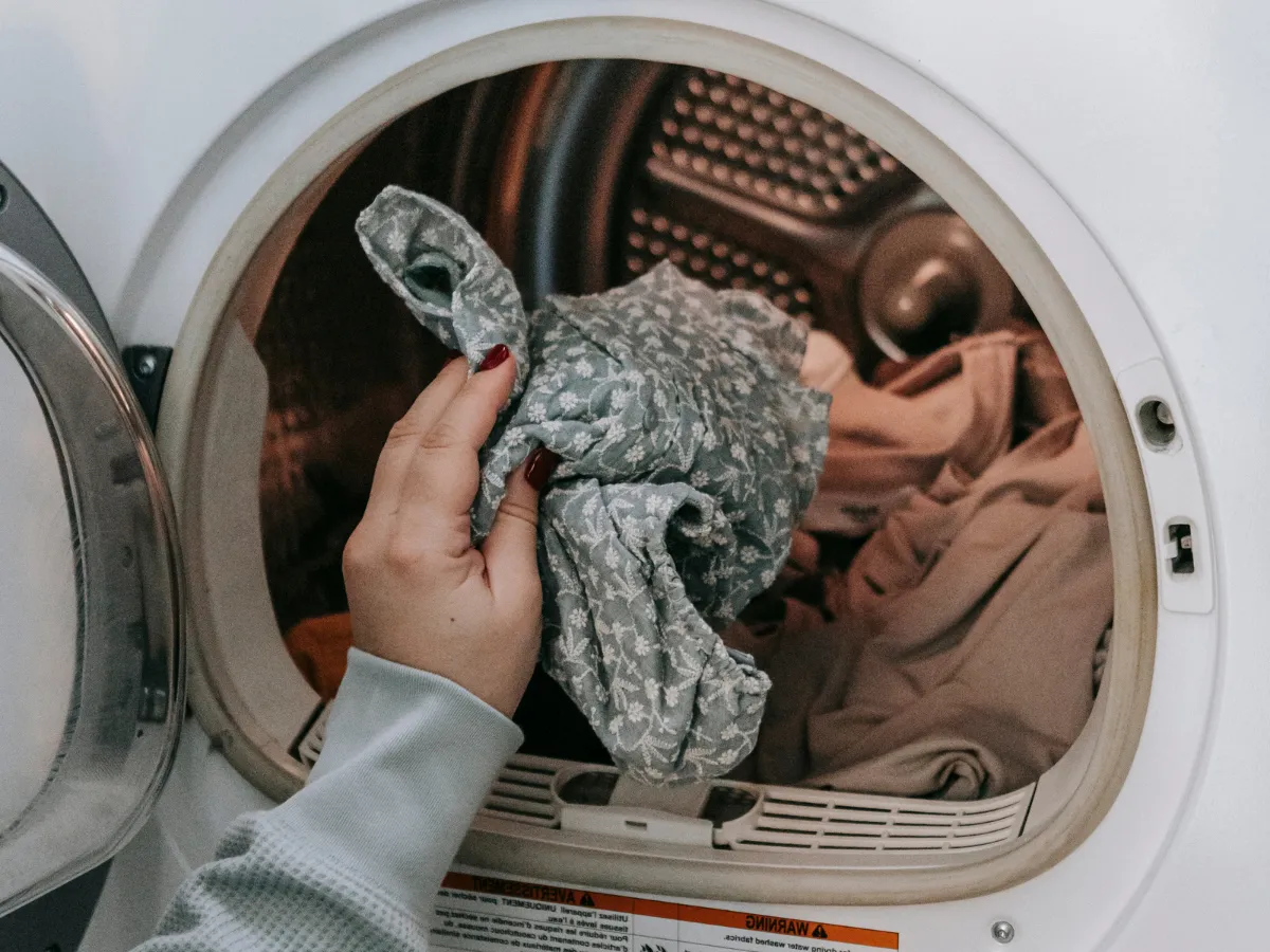 Inside of a washing machine with clothes and symbols of bacteria being eliminated