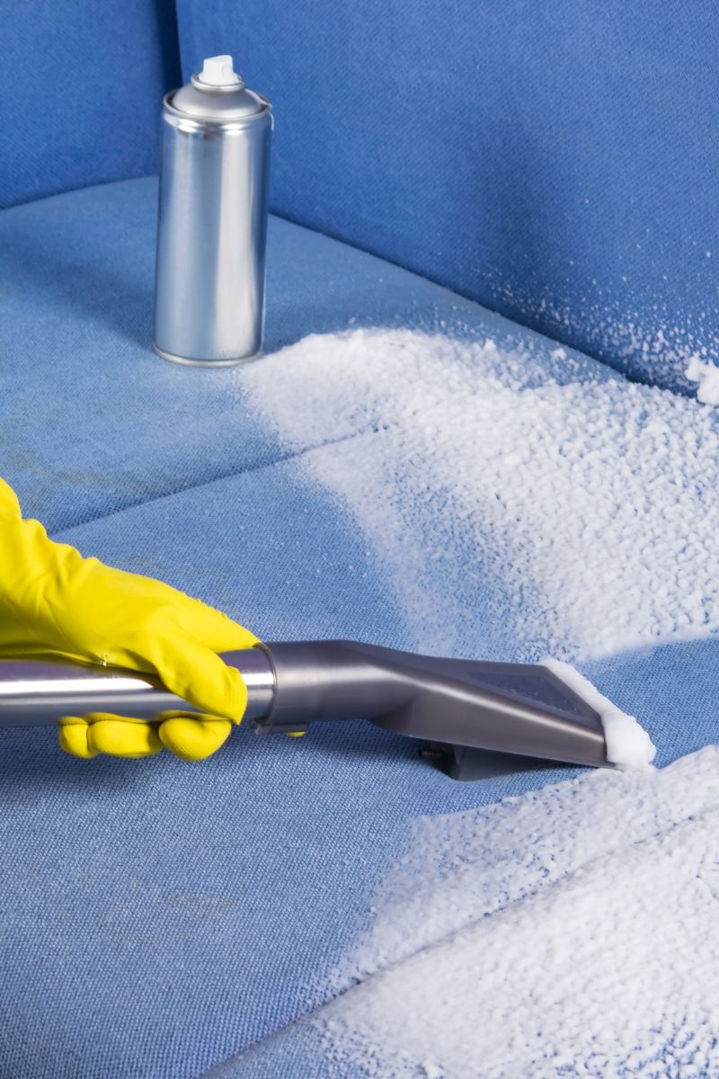 Gloved hand cleaning mold on a sofa using a wet/dry vacuum