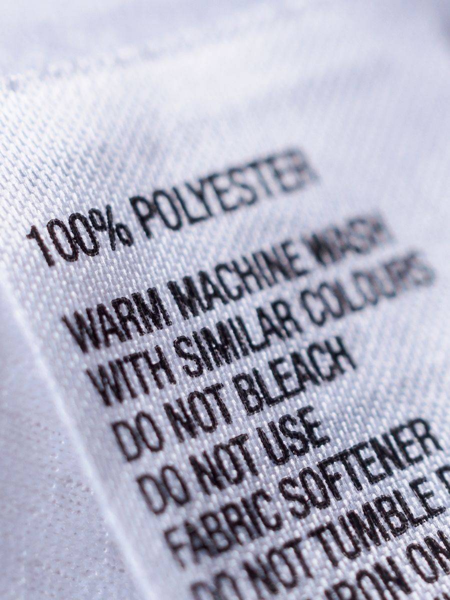 Revisando la etiqueta de composición de una prenda de poliéster