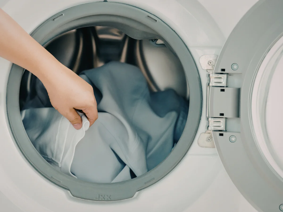 Primer plano de una manta pesada gris doblada y el tambor de una lavadora doméstica