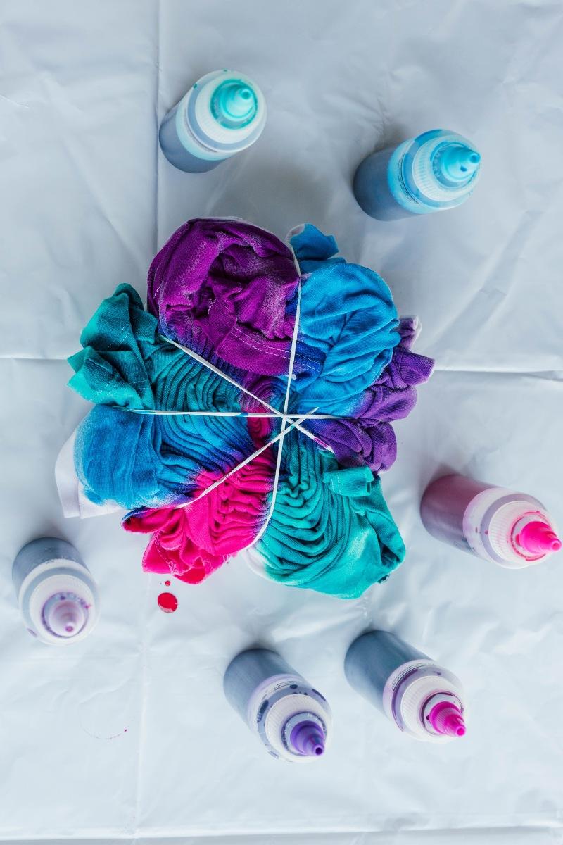 Kit of materials for tie-dye: dyes, rubber bands, gloves, and a white t-shirt.