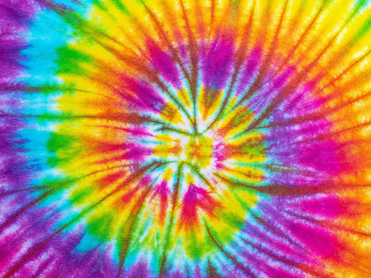 Several t-shirts with different tie-dye designs and colors drying in the sun.